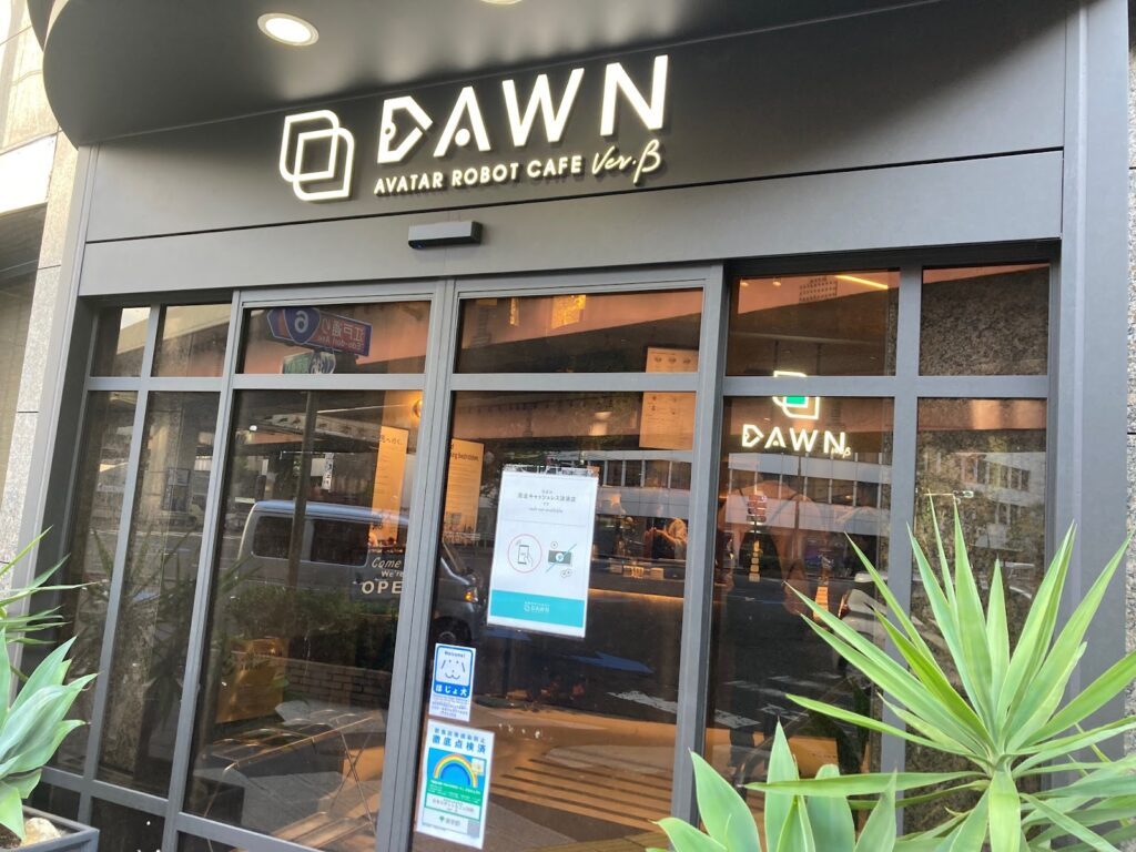 「DAWN」の看板を掲げたカフェの外観。全面ガラス張りの扉で中が見えるようになっている。