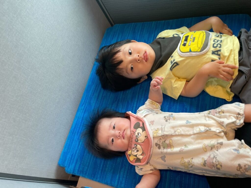 新幹線多目的室の折り畳みベッドに子どもが二人寝転んでいる様子