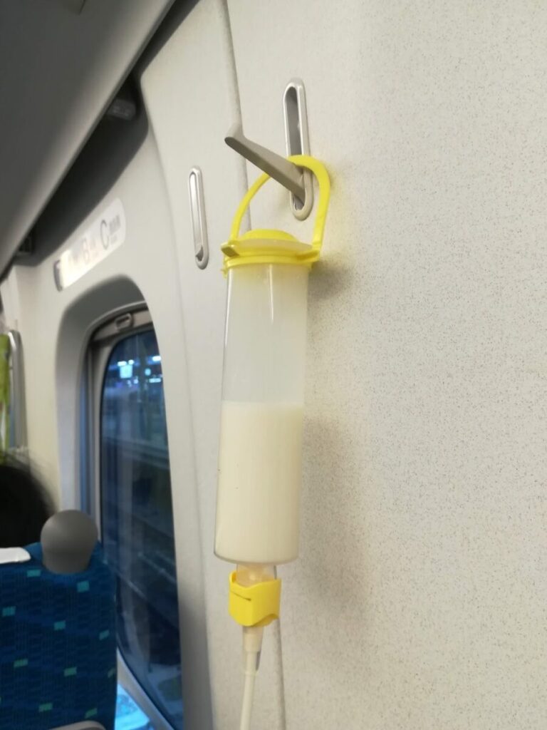 新幹線の座席にあるフックに注入ボトルを吊り下げている