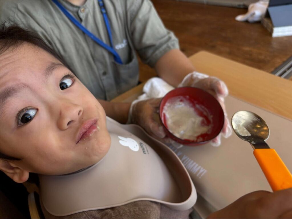 飲み込みが難しいこども用に、ミキサーにかけられた山形名物の芋煮を椅子に座って食べている様子