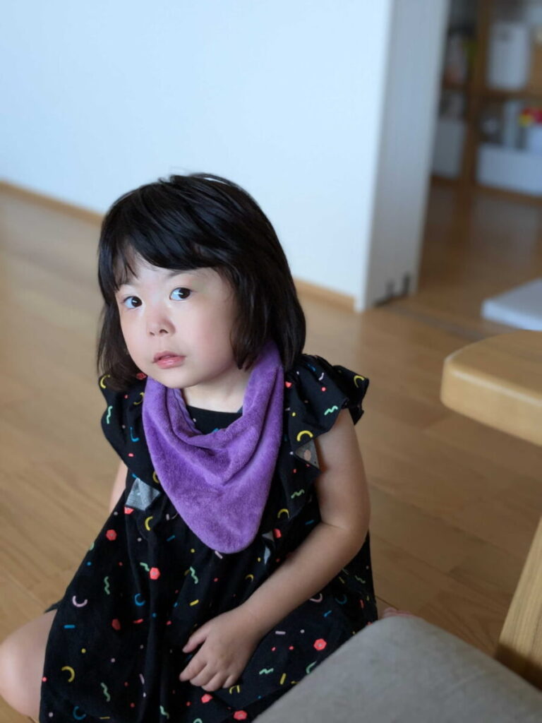 小学生の娘が座ってこちらを見ているところ