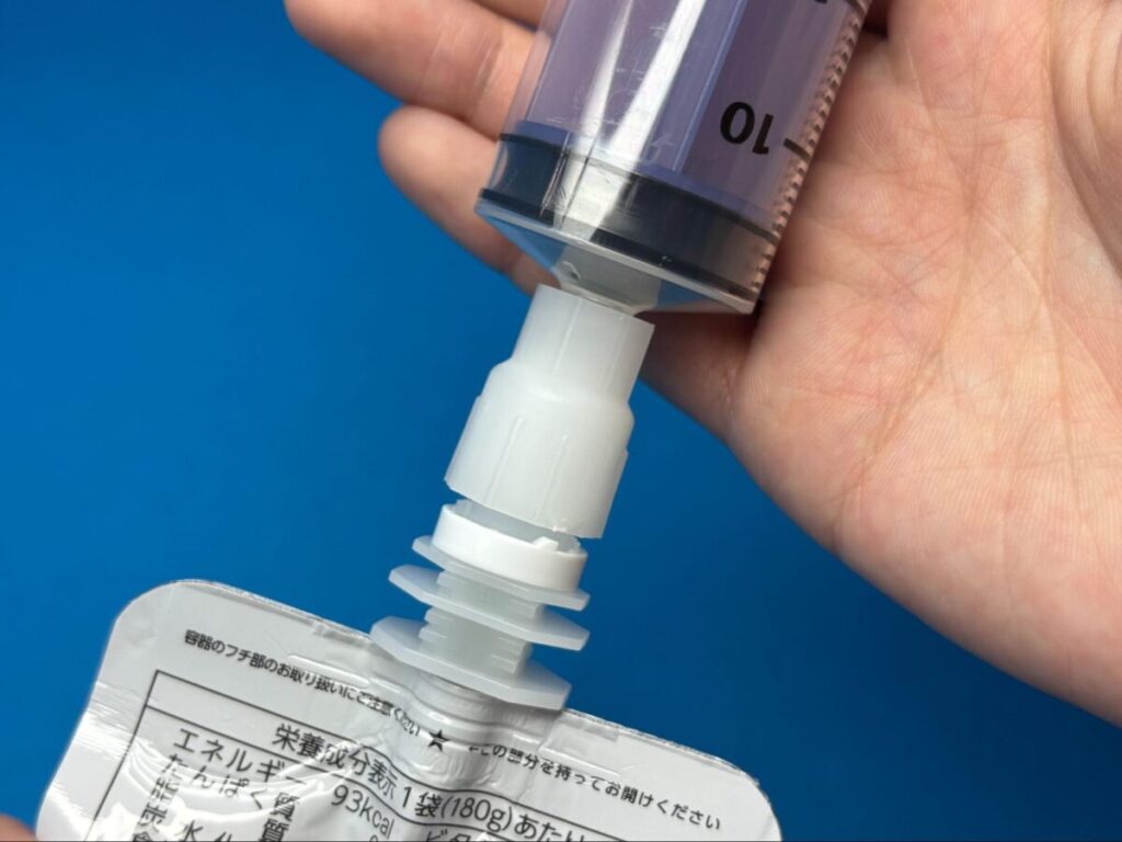 市販のパウチ型飲料と、注入用シリンジを接続するコネクタ。一般的な経管栄養用シリンジにそのまま使えるよう設計