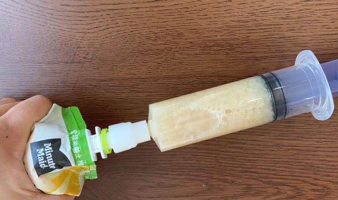 注入用シリンジとパウチ型飲料をコネクタを接続。シリンジ内に飲料の中身が吸い上げられている