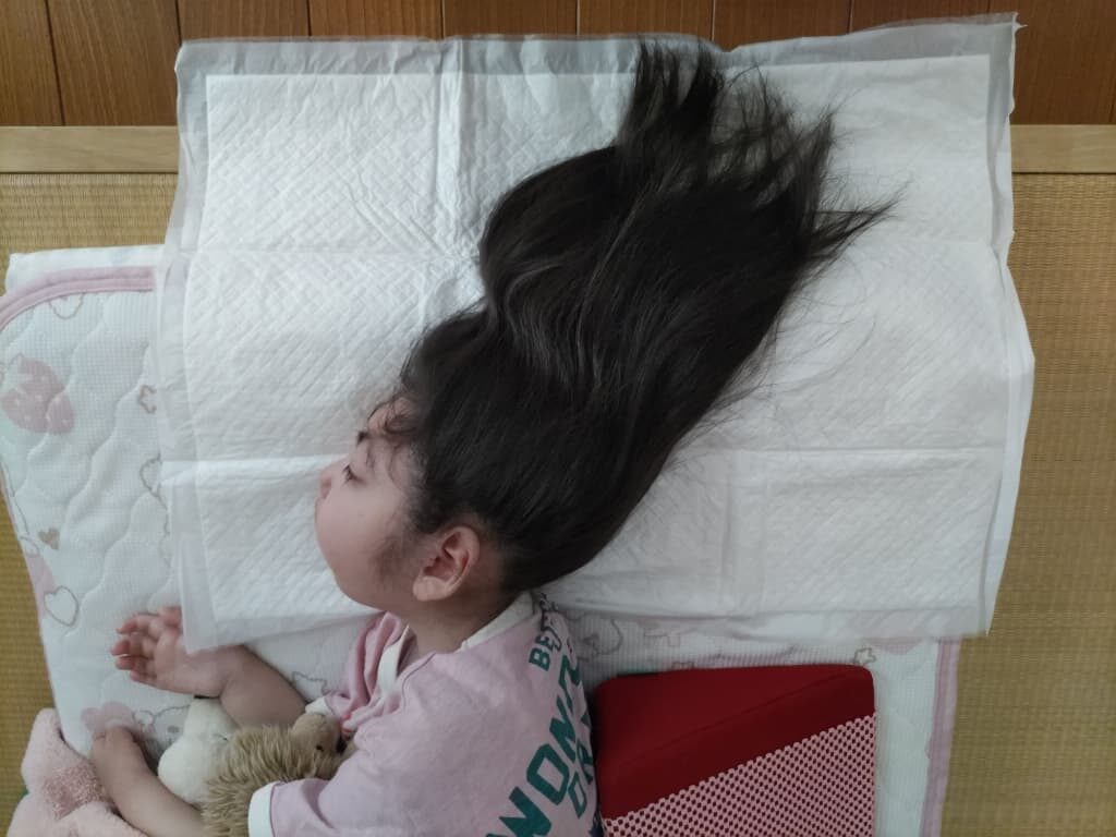 SUSUGU使用前の写真。長い髪の女の子が防水シートの上に頭を乗せて横になっている