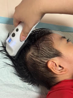 男の子が横向きに横になった状態でSUSUGUを頭にあてられている