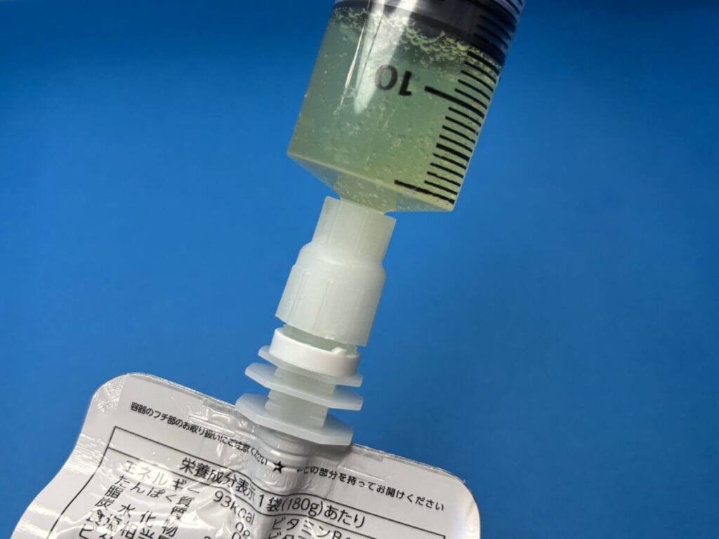 パウチ専用コネクタを使用し、パウチ型飲料と注入用シリンジを接続しているところ