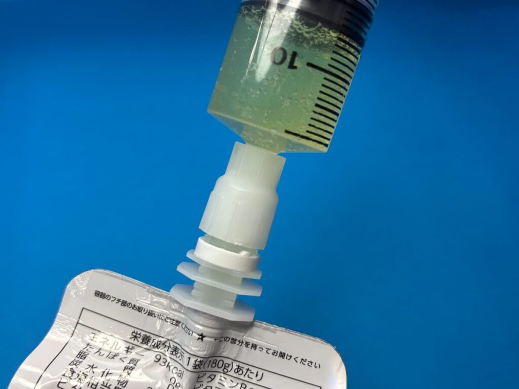 パウチ専用コネクタを使用し、パウチ型飲料と注入用シリンジを接続しているところ