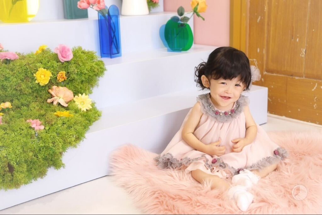 ピンクのドレスを着た女の子が座って微笑んでいる