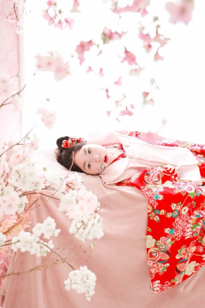 着物を着た女の子が横になってお花を見つめている