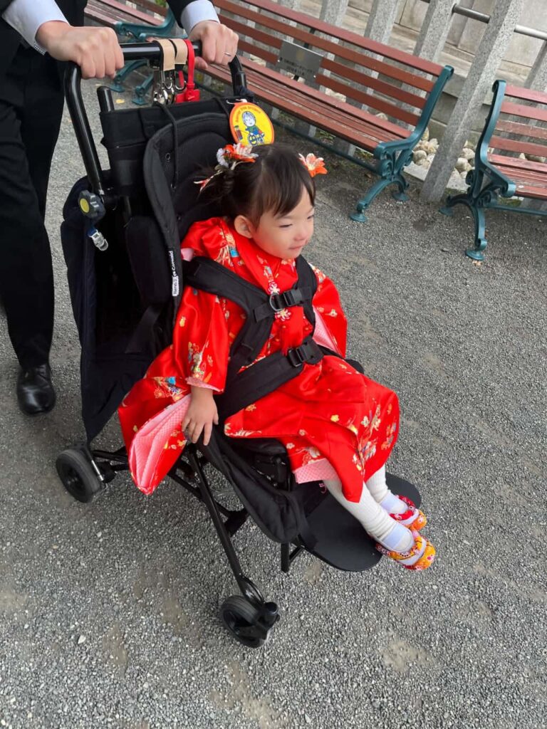七五三の着物を着て、自作の下駄スリッポンを履いて車椅子に乗っている女の子