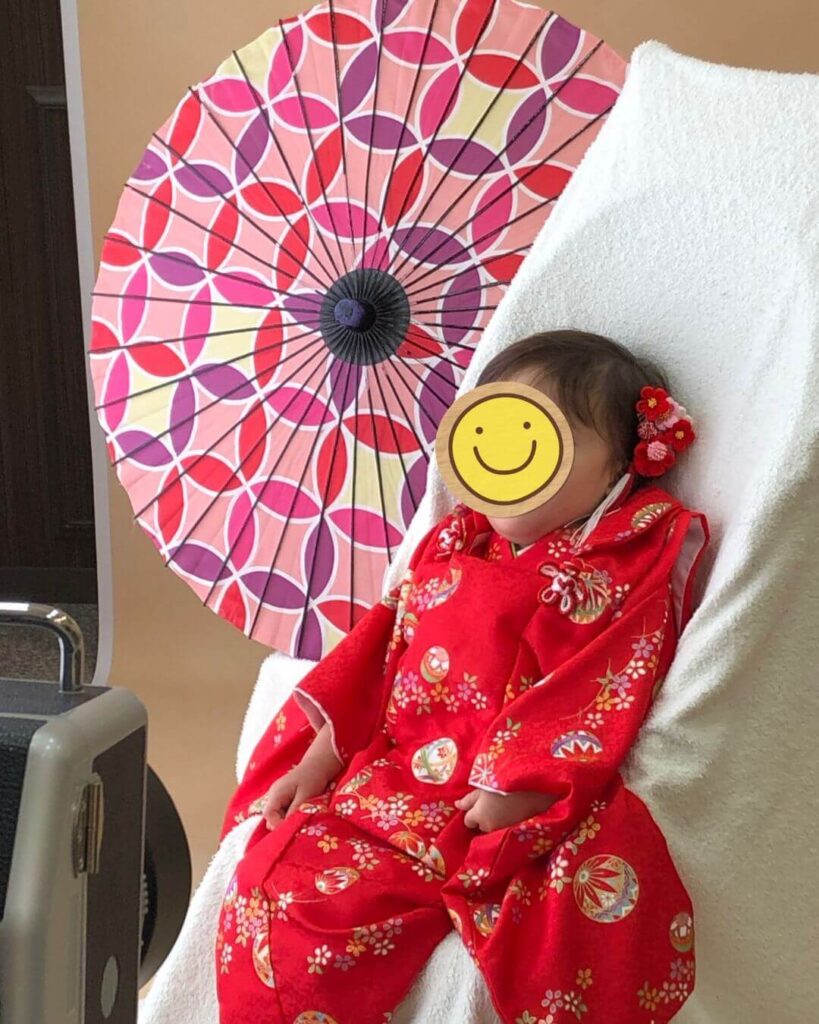 車椅子に座って着物を着て撮影スタジをで七五三の撮影をしている女の子 車椅子には白い布を被せて見えないように工夫されている