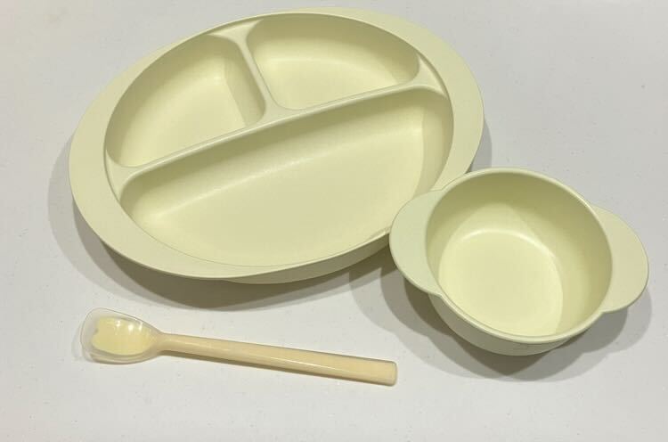 仕切りのあるプレート、小さなボウル、スプーンが白い背景の上に並んで置かれている