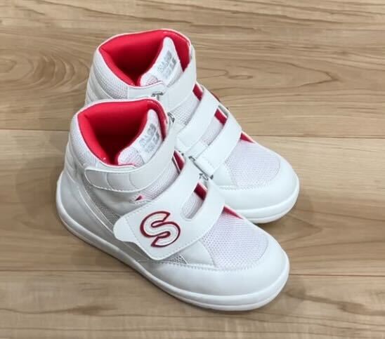 木目の床の上に並べられた、赤い内側が見える白い子ども用のマジックテープ付きシューズ2足の写真