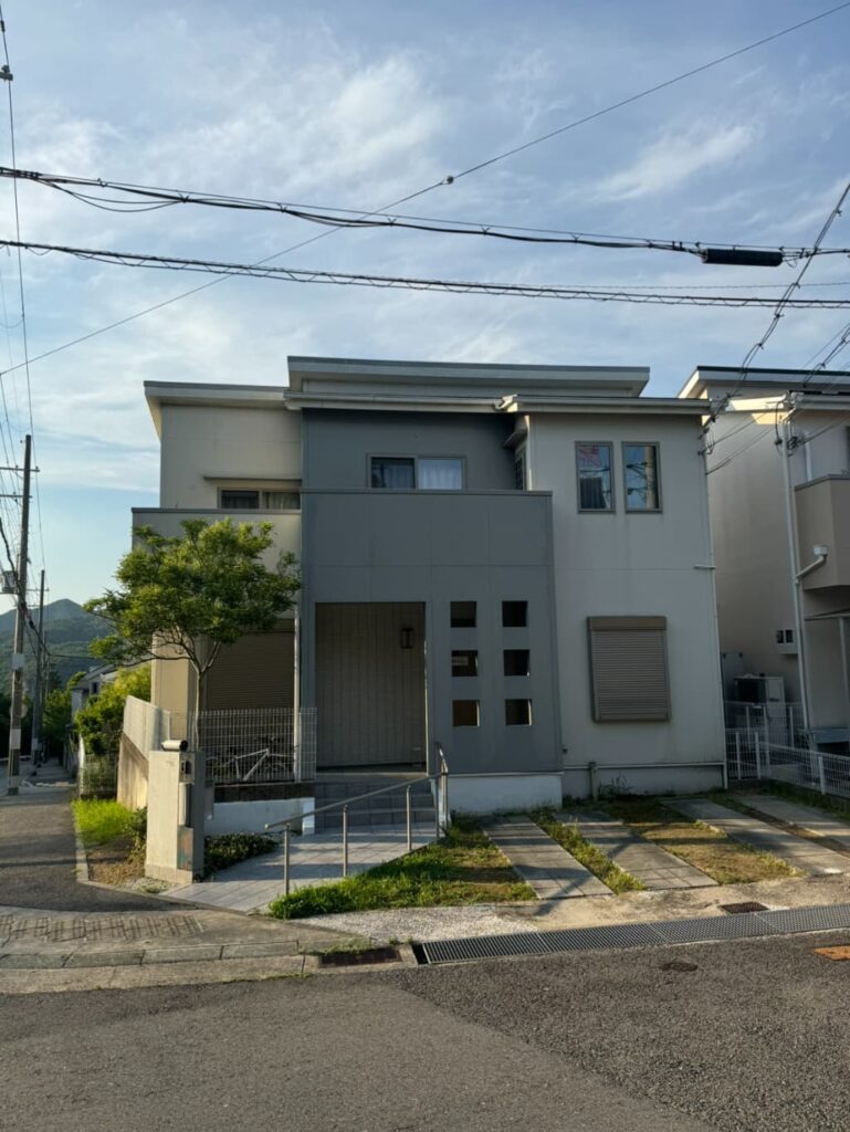 住宅街にある訪問看護ステーションの外観。2階建てで駐車スペースがある