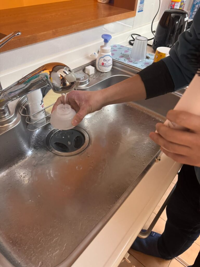 キッチンのシンクでSUSUGUの給水タンクに水道水を注いでいる様子。
