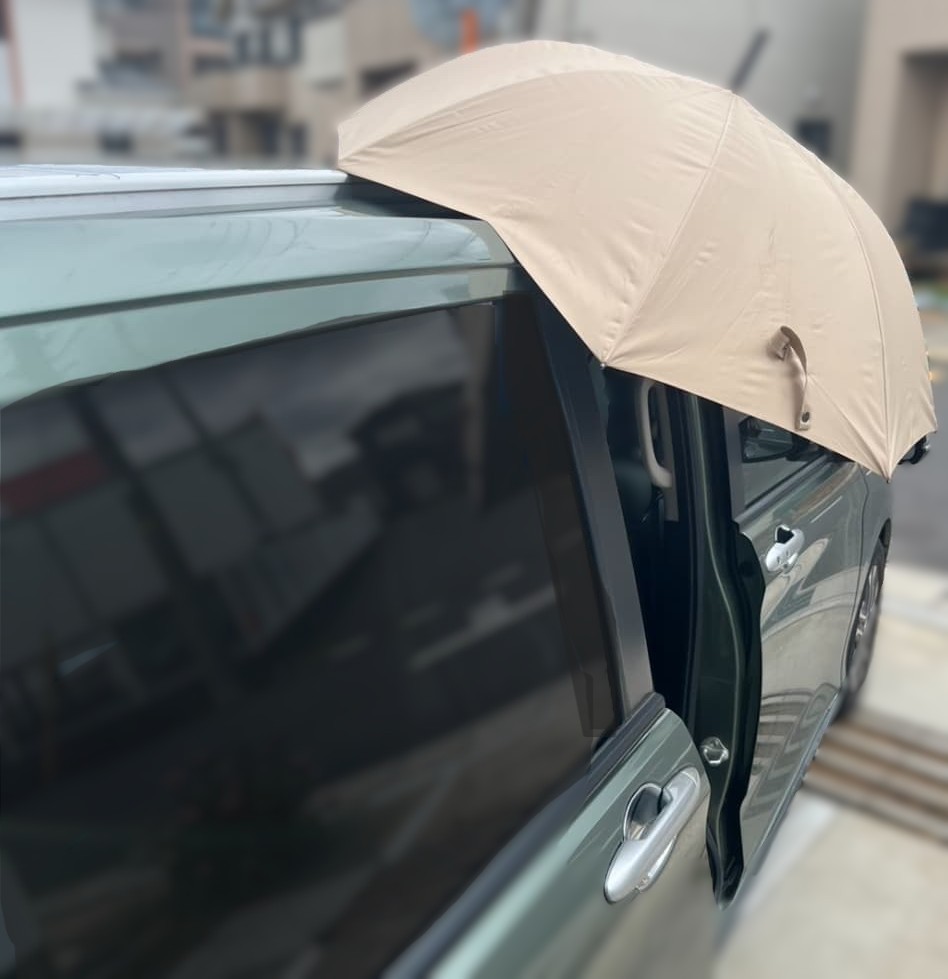 ベージュ色の傘を車の屋根にマグネットで固定し、スライドドアを開けた状態の様子。傘が車体に取り付けられているため、雨の日でも両手を使って子どもの乗せ下ろしや荷物の出し入れがしやすくなる。